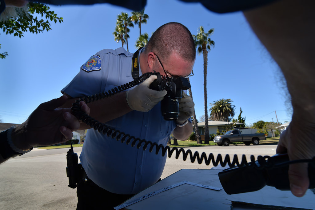 Community Services Officer Ryan Berleth of the Garden Grove PD photographs a boot print from a panel that was kicked-in during a break-in of a home in Garden Grove. Photo by Steven Georges/Behind the Badge OC