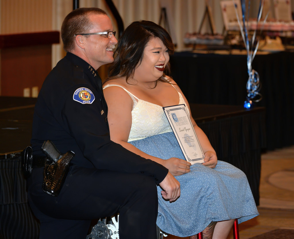 (35:45) Garden Grove Police Chief Todd Elgin kneels down to present Sarah Nguyen with a GGPD chief’s coin award for notifying and assisting Garden Grove police in identifying suspects who stole a U-Haul trailer and van and were using them to transport stolen household belongings. Photo by Steven Georges/Behind the Badge OC