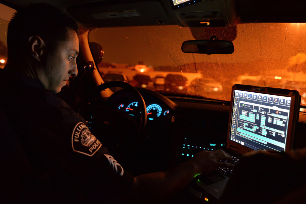 Sgt. Pedram Gharah of Fullerton PD’s ECHO Unit, checks the availability of officers on patrol using the patrol car’s laptop before heading out to patrol the area as the rain comes down. Photo by Steven Georges/Behind the Badge OC