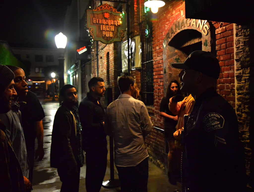 Fullerton PD Cpl. Ryan O’Neil, right, talks to patrons of a local bar early Sunday morning in downtown Fullerton. Photo by Steven Georges/Behind the Badge OC