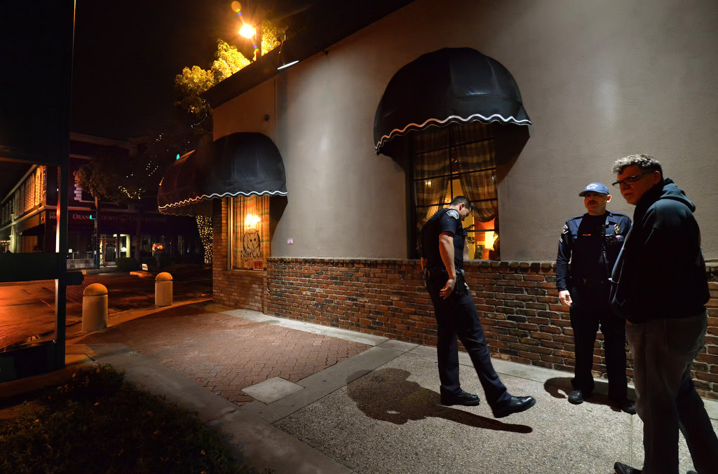 Fullerton PD Officer Davis Crabtree, left, and Cpl. Ryan O’Neil talk to the owner of a downtown business after a window was broken early Sunday morning. Photo by Steven Georges/Behind the Badge OC