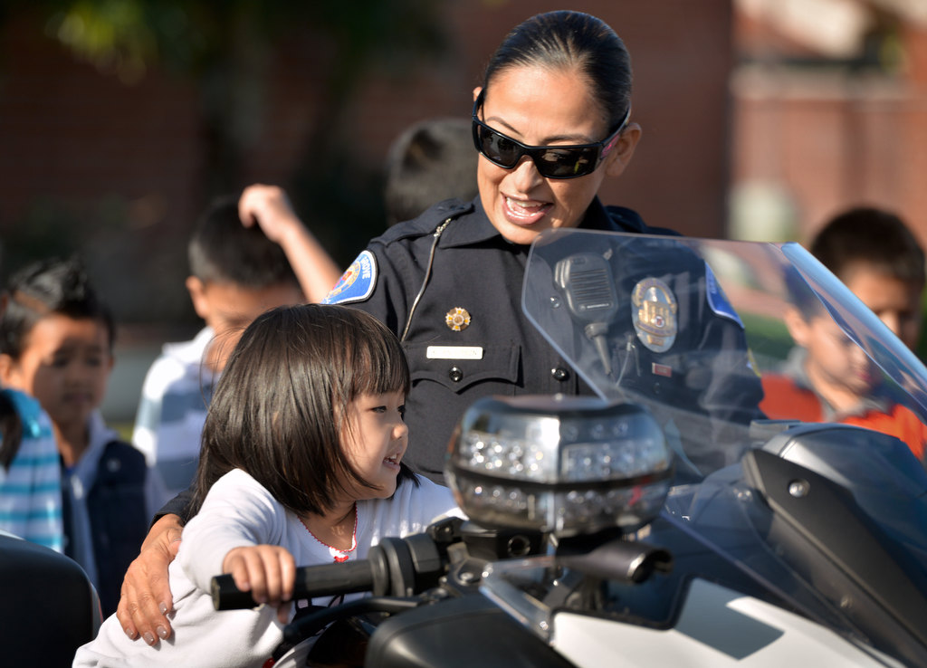 Garden Grove PD Officer Kathy Anderson gives Nhi Do a chance to sit on her police motorcycle during a visit to Anderson Elementary in Garden Grove. Photo by Steven Georges/Behind the Badge OC