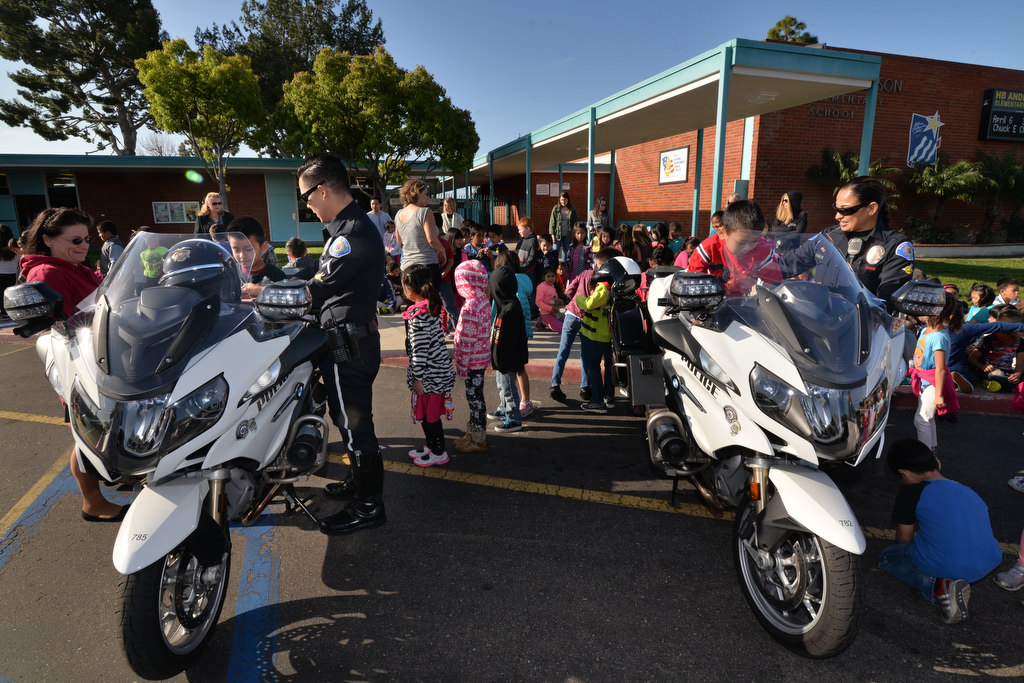 Garden Grove motorcycle officerÕs Royce Wimmer, left, and Kathy Anderson give kindergarten and first graders from Anderson Elementary School in Garden Grove a chance to sit on a real police motorcycle during a visit to talk about bicycle safety. Photo by Steven Georges/Behind the Badge OC