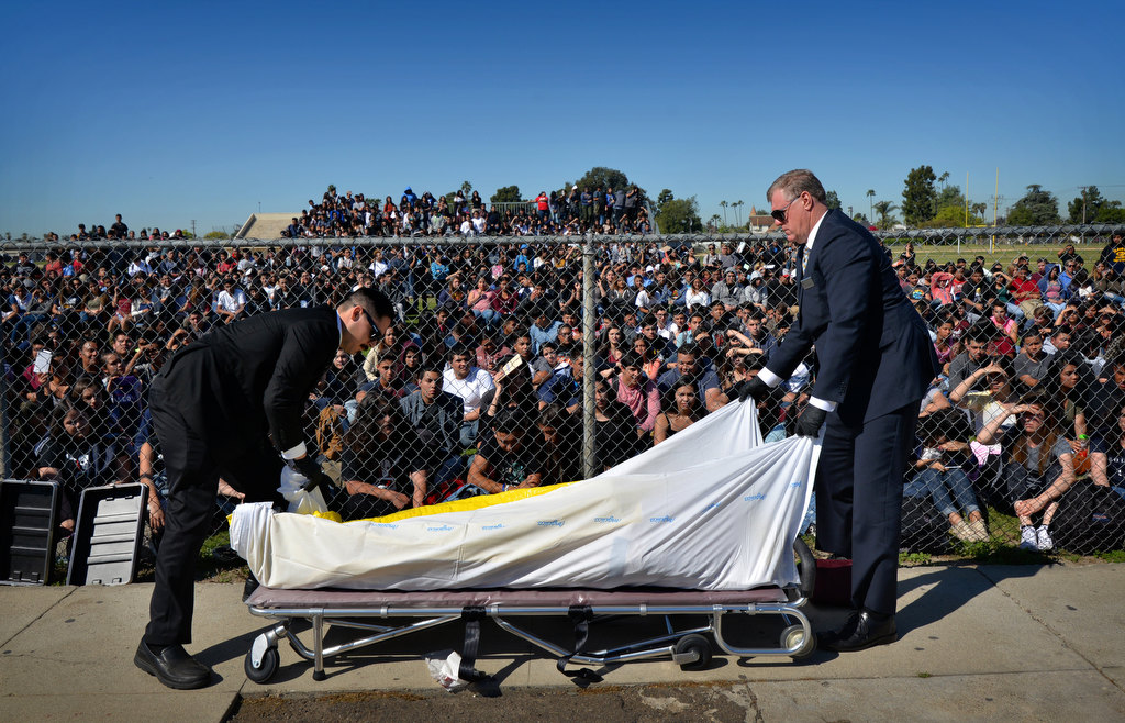 Members of a local funeral home prepare the body of a person playing a deceased car crash victim in front of students at Anaheim High School. Photo by Steven Georges/Behind the Badge OC