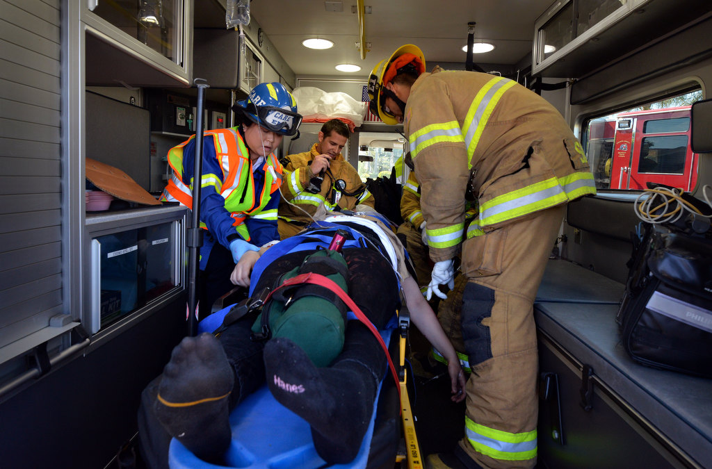 Rescue crews from Anaheim Fire & Rescue bring a simulated injured passenger to a waiting ambulance during a staged drunk driving accident in front of Anaheim High School. Photo by Steven Georges/Behind the Badge OC