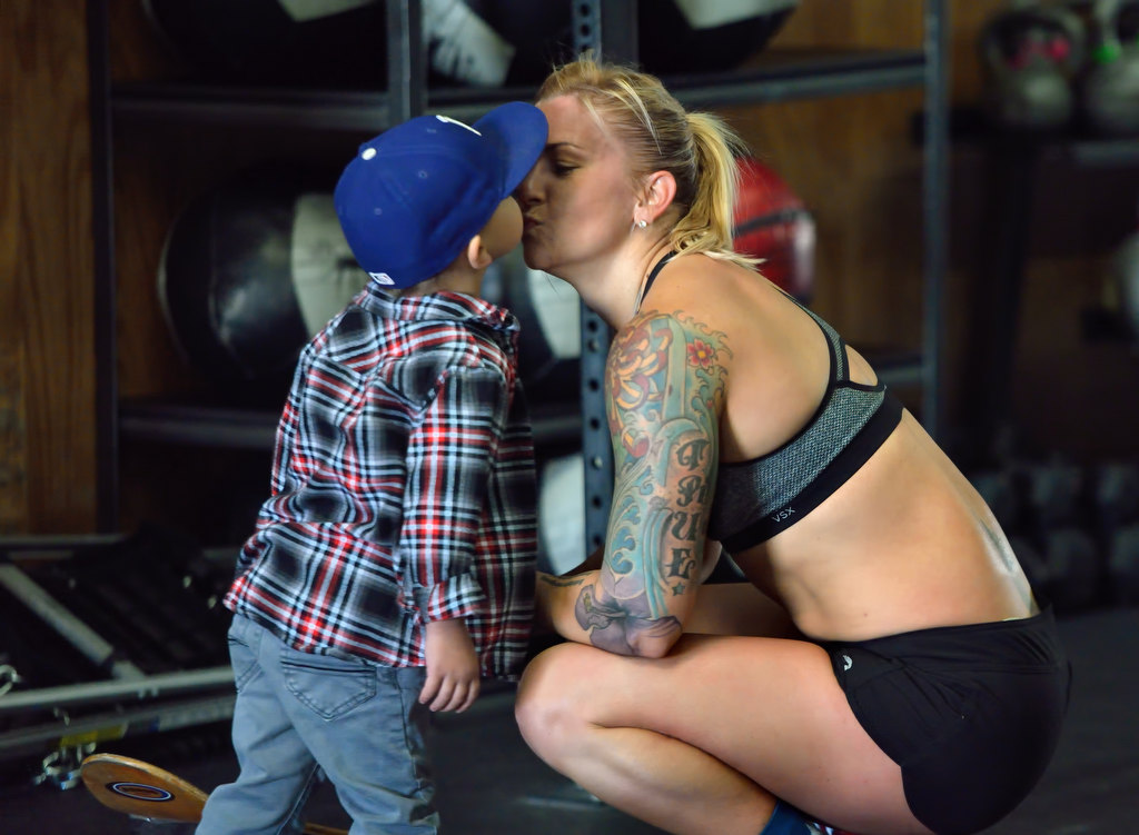 Anaheim PD Officer Merisa Leatherman gets a kiss from her 3-year-old son Drew Downs after her timed workout at the CrossFit CrownTown in Corona. Photo by Steven Georges/Behind the Badge OC