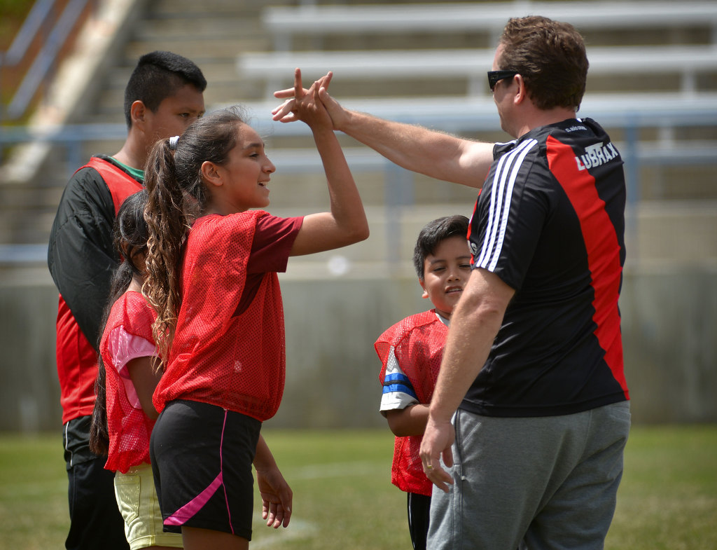 Fullerton PD Cpl. Joel Craft gives kids high-fives at the conclusion of the final match of the OC GRIP soccer camp at Cal State Fullerton’s soccer stadium. Photo by Steven Georges/Behind the Badge OC