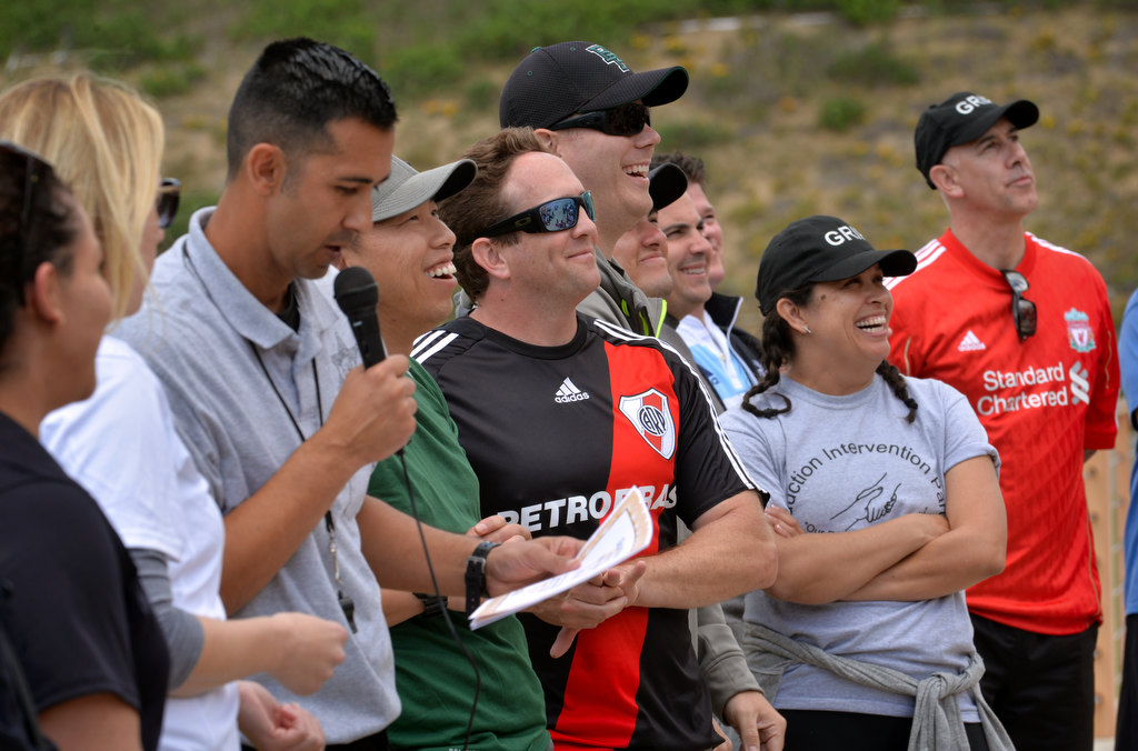 Daniel Arreguin, left, reads the names of kids receiving awards with Fullerton PD’s Cpl. Billy Phu and Cpl. Joel Craft next to him at the conclusion of the OC GRIP soccer camp Cal State Fullerton’s soccer stadium. Photo by Steven Georges/Behind the Badge OC