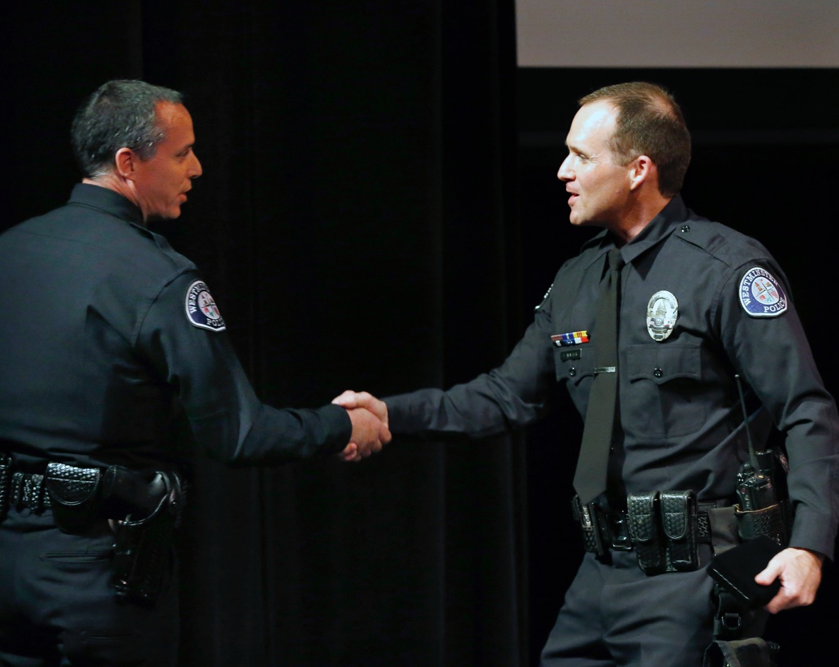 Cmdr. Al Panella shakes Officer Tim Walker's hand as he presents him with the Medal of Merit for his work on a 2015 murder case. Photo by Christine Cotter/Behind the Badge OC