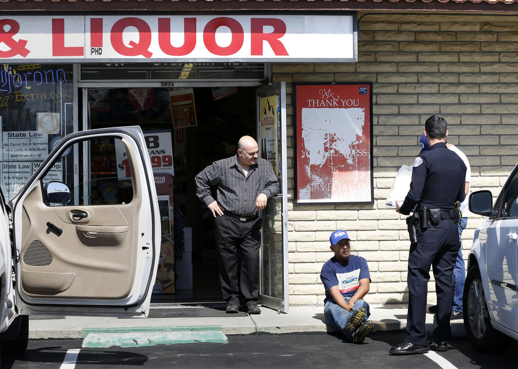 A man suspected of buying alcohol for a minor is questioned by Garden Grove Police Officer Austin Laverty, right, outside of a liquor store.  Photo by Christine Cotter