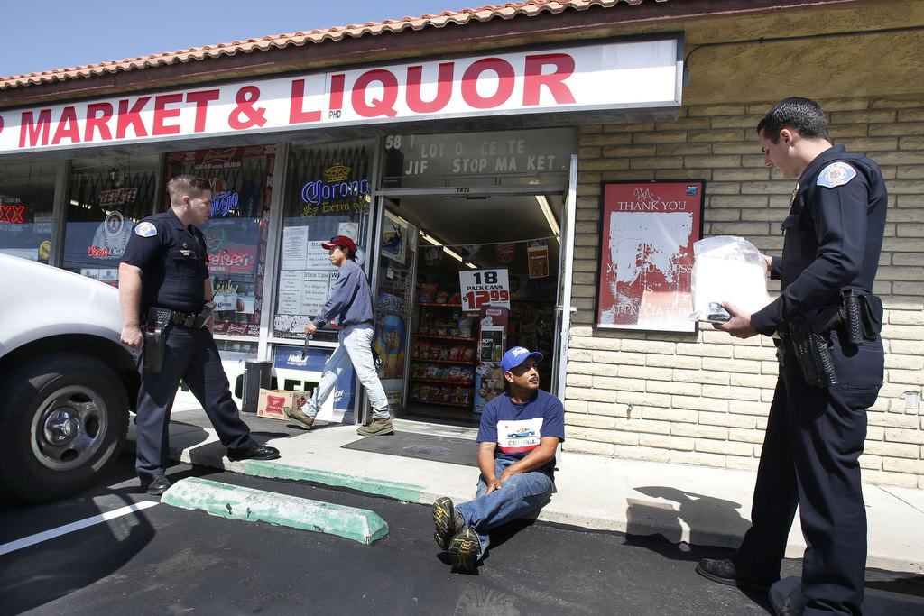 Garden Grove Police Officer Danny Mihalik, left and  Officer Austin Laverty question a suspect during the department's undercover alcohol purchase sting. Photo by Christine Cotter