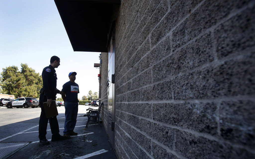 A man suspected of buying alcohol for a minor is taken to the station by Garden Grove Police Officer Austin Laverty. The department conducted an undercover alcohol purchase sting called Shoulder Tap. Photo by Christine Cotter