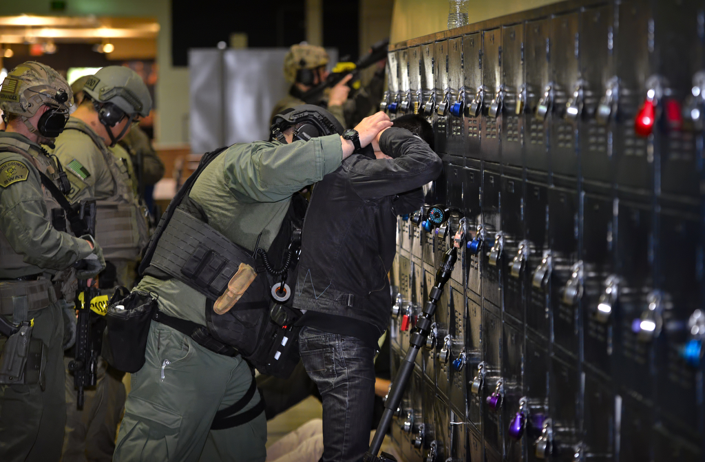 Taking no chances that a suspect may be hiding among the victims, people rescued from a room are searched before being led out of the danger zone during an active shooter drill at Sonora High School. Photo by Steven Georges/Behind the Badge OC