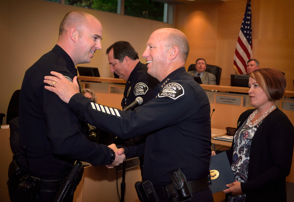 Fullerton PD Officer Scott Flynn, left, is congratulated by Fullerton Police Chief Dan Hughes at a city council meeting as he is recognized for his 61 DUI arrests. Fullerton Mayor Jennifer Fitzgerald is right holding his proclamation. Photo by Steven Georges/Behind the Badge OC