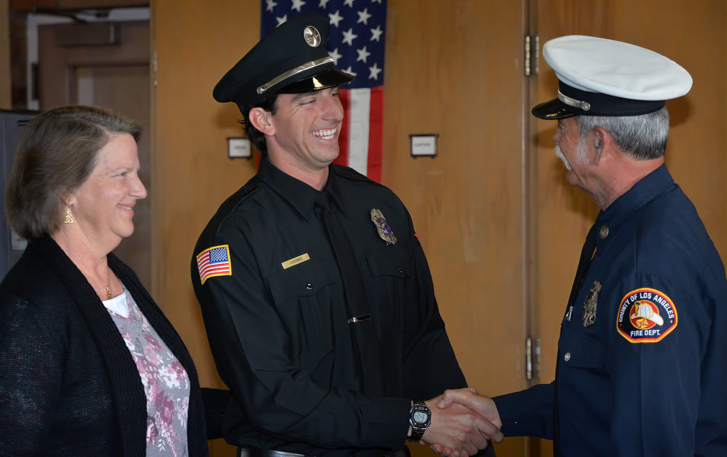 Fullerton Engineer Kyle Coggins, center, smiles after his (father?) Los Angeles County Fire Department Captain Michael Coggins pinned his new badge on him during the Fullerton Fire Department’s promotional ceremony. Photo by Steven Georges/Behind the Badge OC