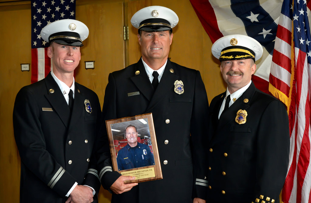 Fullerton FD Captain Brian Seymour receives the Firefighter of the Year award = 2016 from Fullerton FD Captain/Paramedic Jon Fugitt, left, and Fullerton/Brea Fire Chief Wolfgang Knabe during the department’s promotional ceremony at Fire Station 1. Photo by Steven Georges/Behind the Badge OC