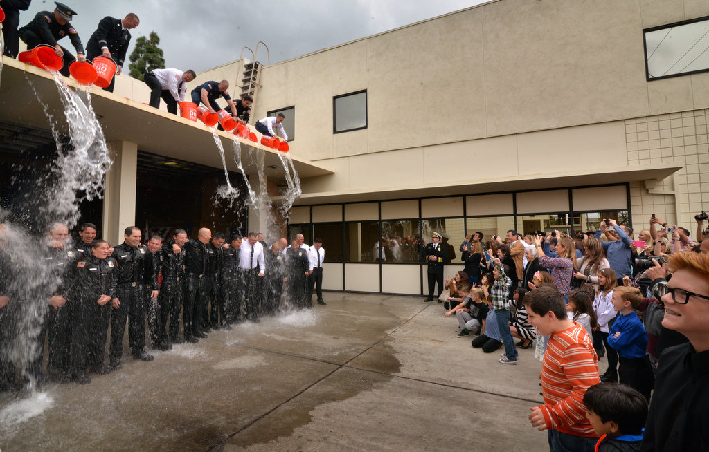 Family and friends gather as members of the Fullerton Fire Department are dowsed with buckets of water during a tradition at the conclusion of a promotional ceremony at Fire Station 1. Photo by Steven Georges/Behind the Badge OC