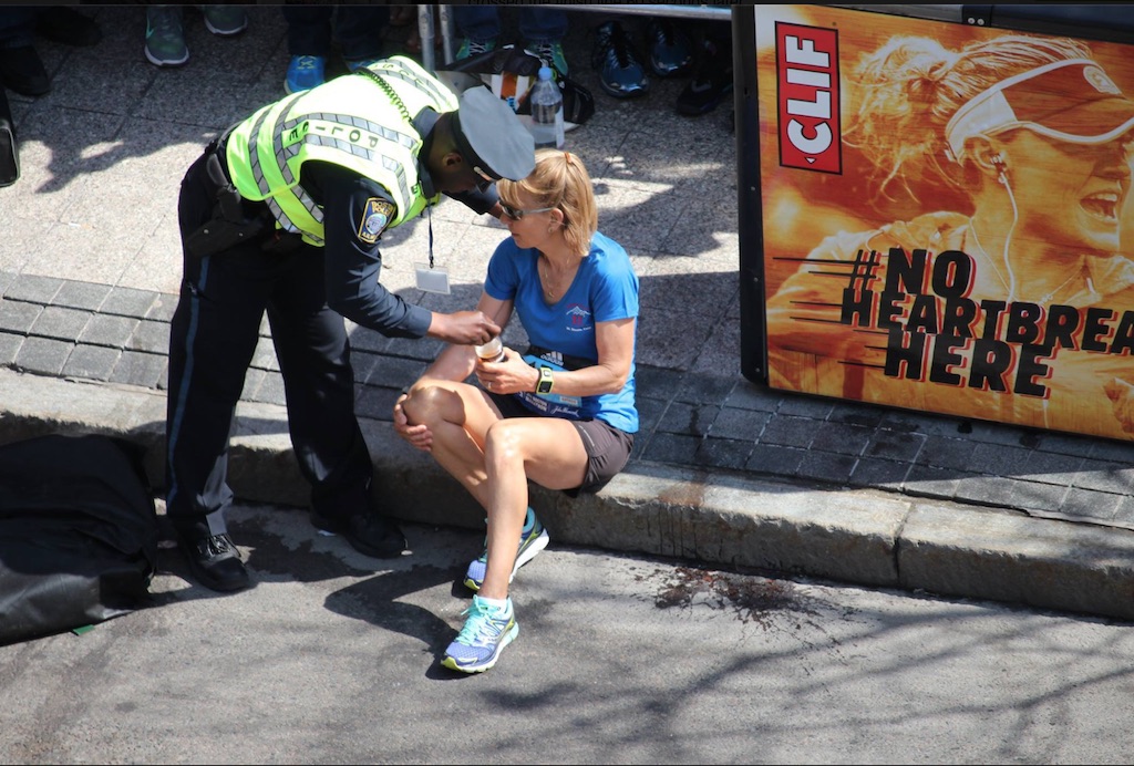 A Boston PD officer hands a weary runner a bottle of water at the end of the Boston Marathon. A bystander watched as the officer encouraged the woman to finish the race. Photo from the Boston PD's Facebook page. 