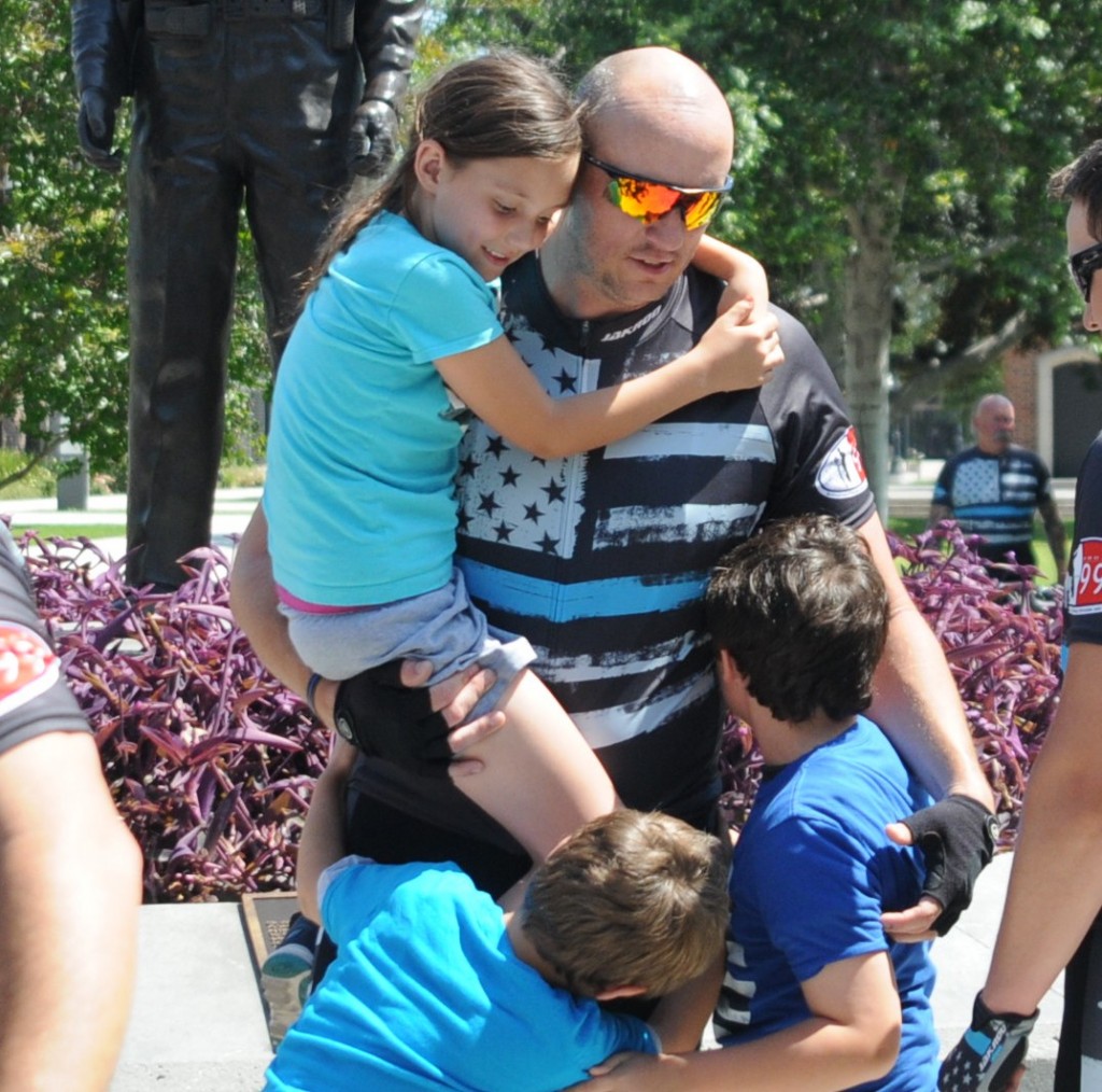 Officer Jeremy Fletcher gets hugs from his children after returning from a 630-mile ride to honor fallen officers. Photo by Lou Ponsi/Behind the Badge OC 