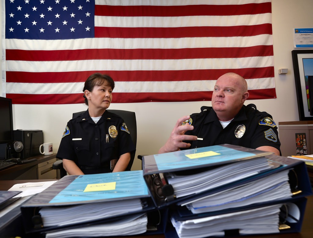 Anaheim PDÕs Lt. Kelly Jung, left, and Sgt. Marc Brucks talk about all the work that goes into recruiting an officer for the department, both internal promotions as well as hiring from outside. The books in front of them are background checks, one book for each applicant. Photo by Steven Georges/Behind the Badge OC