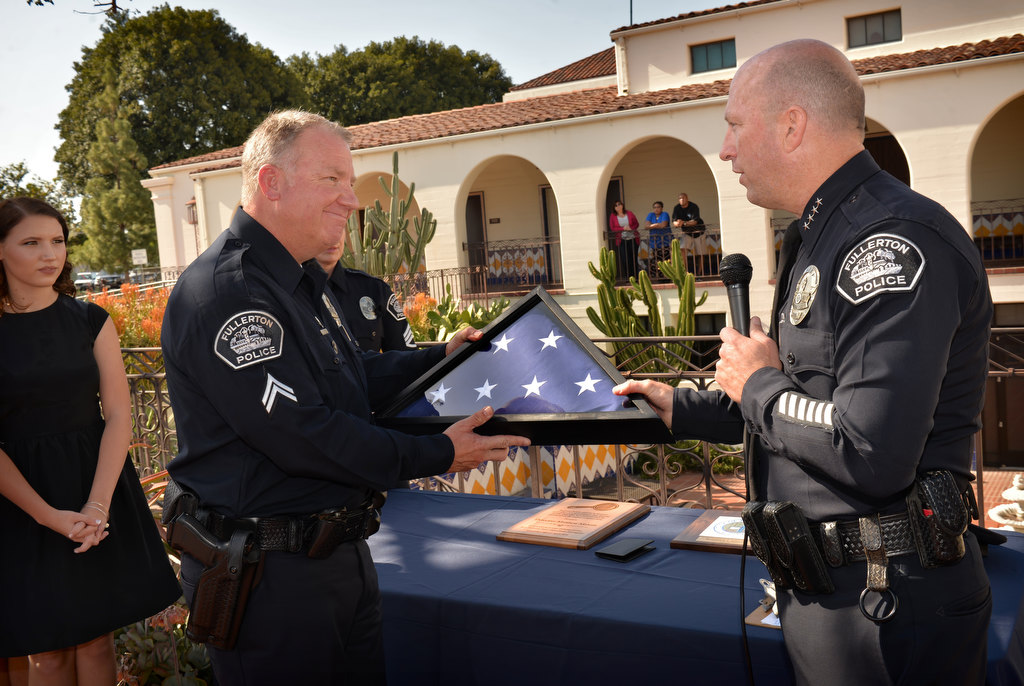 Fullerton PD Cpl. Matt Malone receives a flag that was flown over police headquarters from Chief Dan Hughes during Malone’s retirement ceremony. Photo by Steven Georges/Behind the Badge OC