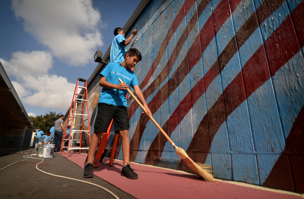 Diego Delagadillo, 12, former student of Valencia Park Elementary School helps prepare a faded wooden wall at the same school for repainting during the Love Fullerton community volunteer event. Photo by Steven Georges/Behind the Badge OC