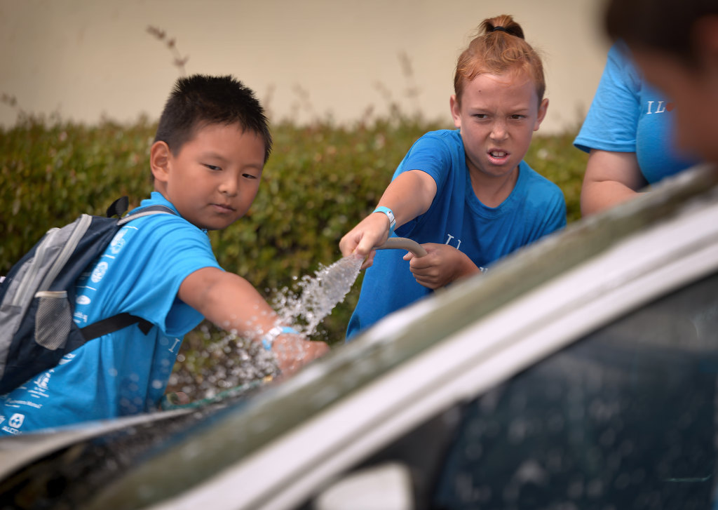 Jonathan Chien, 9, of Yorba Linda, left, and Jonah Blake, 12, of Fullerton, help wash one of the city cars in the parking lot of the Fullerton Police department, part of the Love Fullerton community event. Photo by Steven Georges/Behind the Badge OC