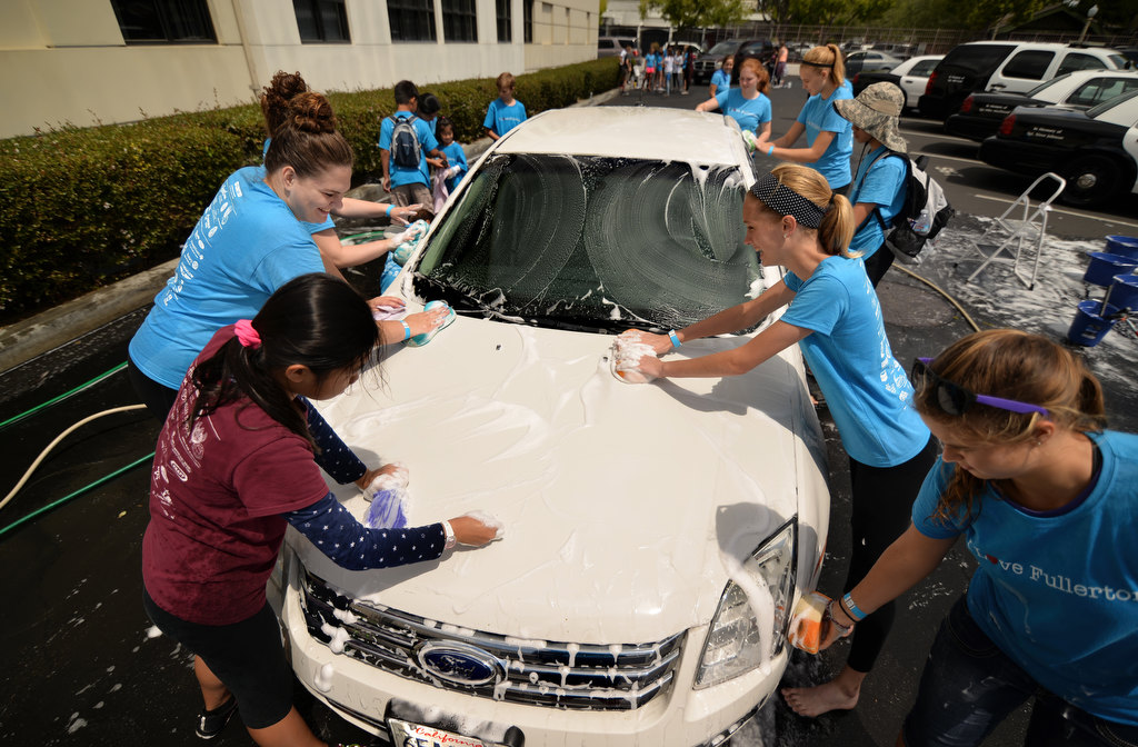 Volunteers wash city cars in the parking lot of the Fullerton Police department, part of the Love Fullerton community event. Photo by Steven Georges/Behind the Badge OC