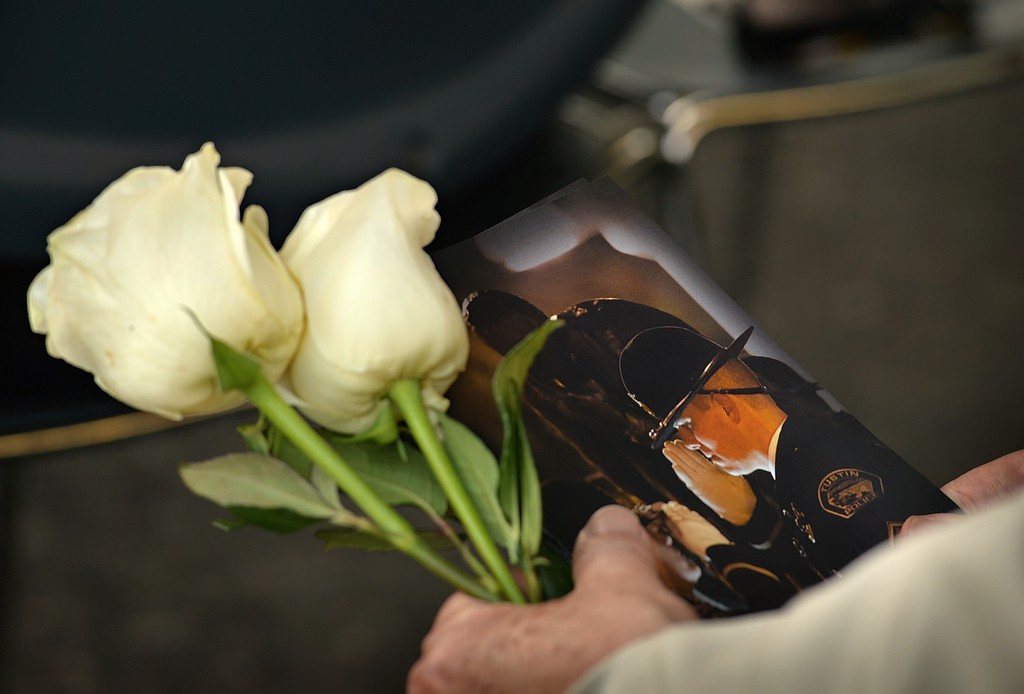 A man holds a Wally Karp memorial ceremony program and flowers that would later be placed at the base of Tustin PD’s memorial statue. Photo by Steven Georges/Behind the Badge OC