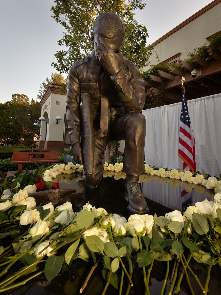 White roses, and a few red roses from Officer Karp’s family, left, are placed at the base of Tustin PD’s memorial statue at the conclusion of the Wally Karp memorial service. Photo by Steven Georges/Behind the Badge OC