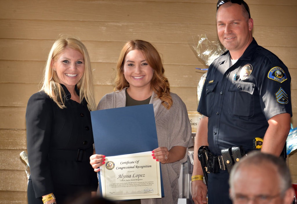 G.R.I.P. Teacher Mentor Alyssa Lopez receives recognition from xxx, left, and Anaheim PD Sgt. Brennan Leininger during a recognition ceremony at the Anaheim House of Blues in Downtown Disney. Photo by Steven Georges/Behind the Badge OC