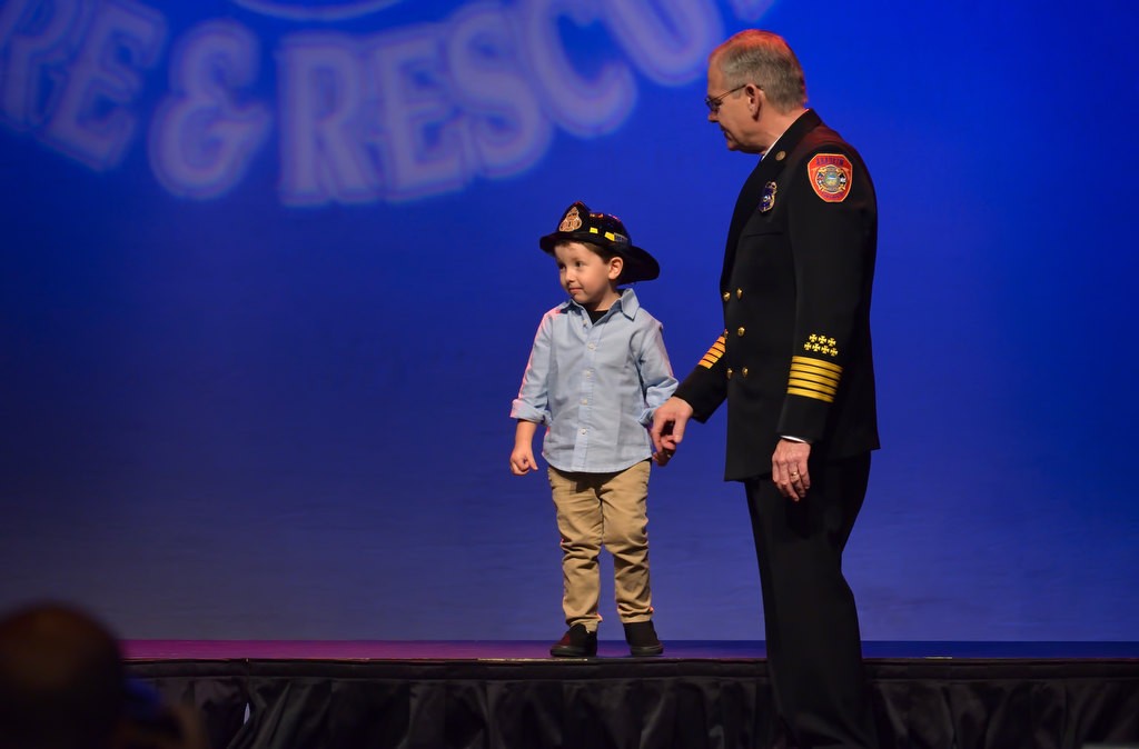 Brayden White seems to enjoy the stage too much to leave after his father, Michael White, received his new AF&R Firefighter badge. Anaheim Fire & Rescue Chief Randy Bruegman gives him an extra minute to enjoy the limelight. Photo by Steven Georges/Behind the Badge OC