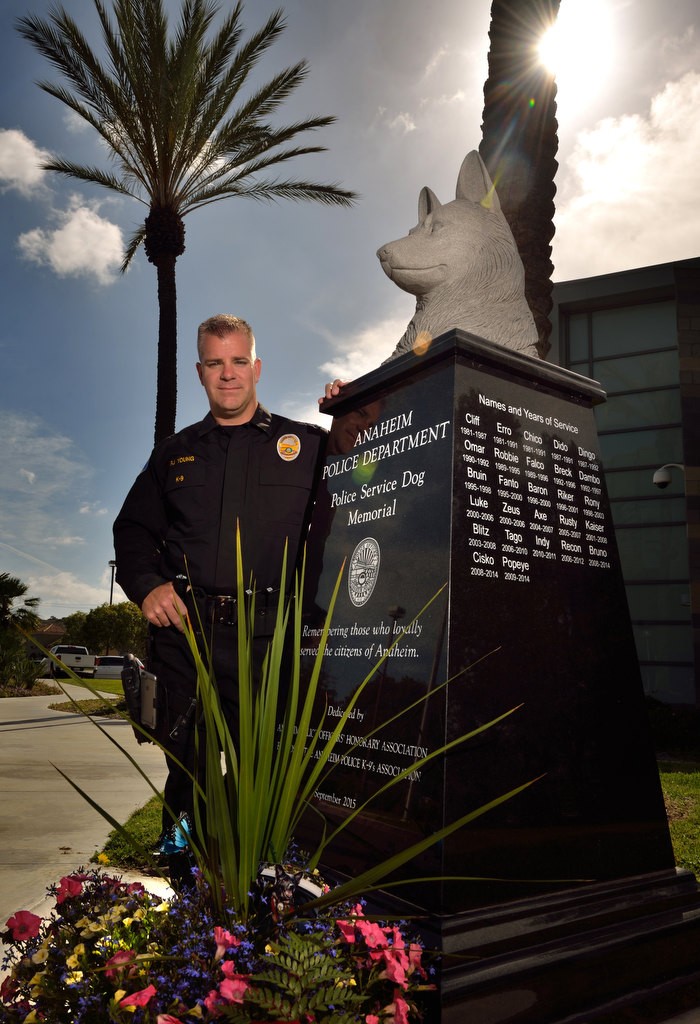 Officer RJ Young stands next to Anaheim PD’s Police Service Dog Memorial located at Anaheim PD's East Station. Young’s former K-9 partner, Bruno, recently passed away as a direct result from injuries sustained by a shooting two years ago. Bruno’s name is included with the other APD K-9’s that have served the city of Anaheim. Photo by Steven Georges/Behind the Badge OC