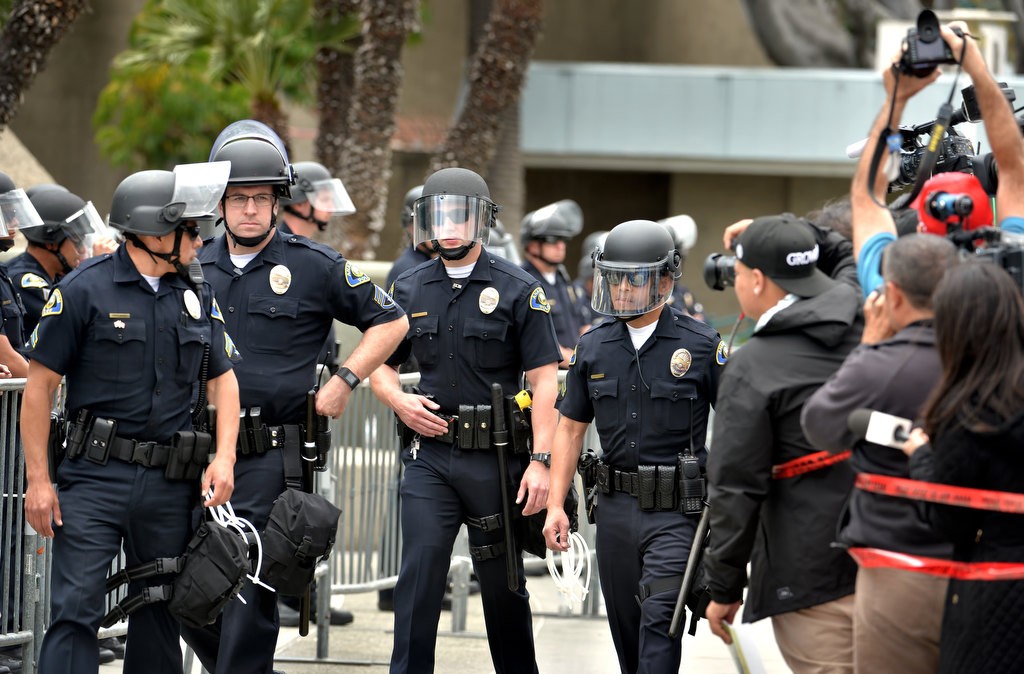 Anaheim Police Officers walk by Donald Trump protesters and the media as both sides kept to their side of the barricade in front of the Anaheim Convention Center. Photo by Steven Georges/Behind the Badge OC