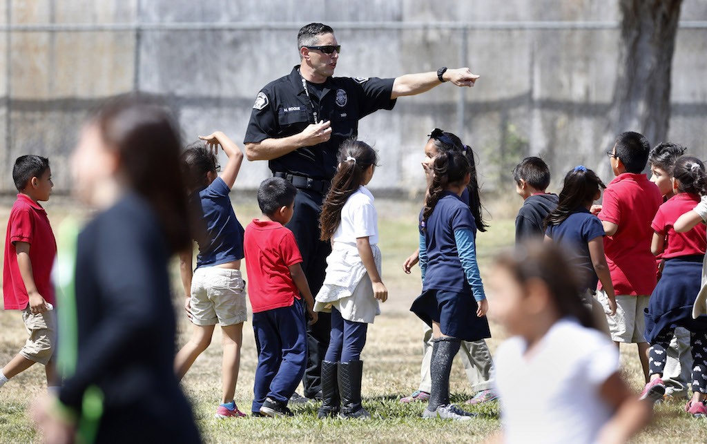 Tustin Police Department's Matthew Roque directs a group of students during a run club program at Heideman Elementary School.  Photo by Christine Cotter/Behind the Badge OC 