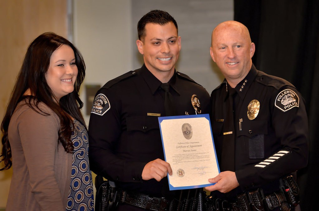 Marcus Saenz stands with his fiancée, Tatiana, and Chief Dan Hughes as a new Fullerton police officer. Photo by Steven Georges/Behind the Badge OC