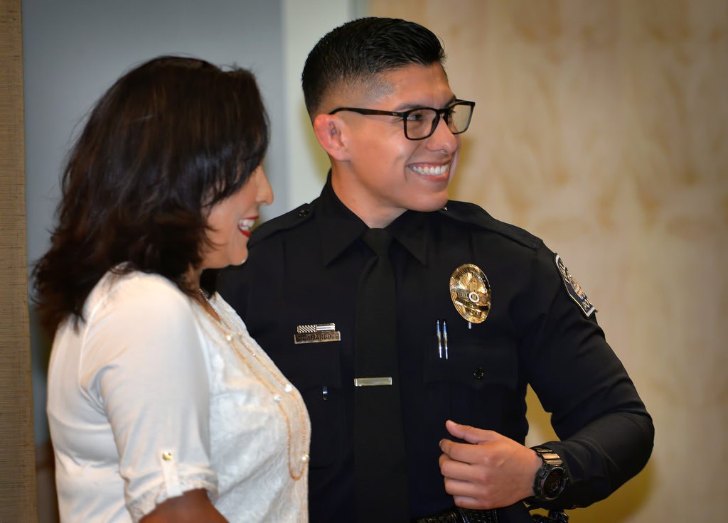 Marco Camargo smiles after receiving his new badge as a Fullerton police officer from his mother Rosa. Photo by Steven Georges/Behind the Badge OC