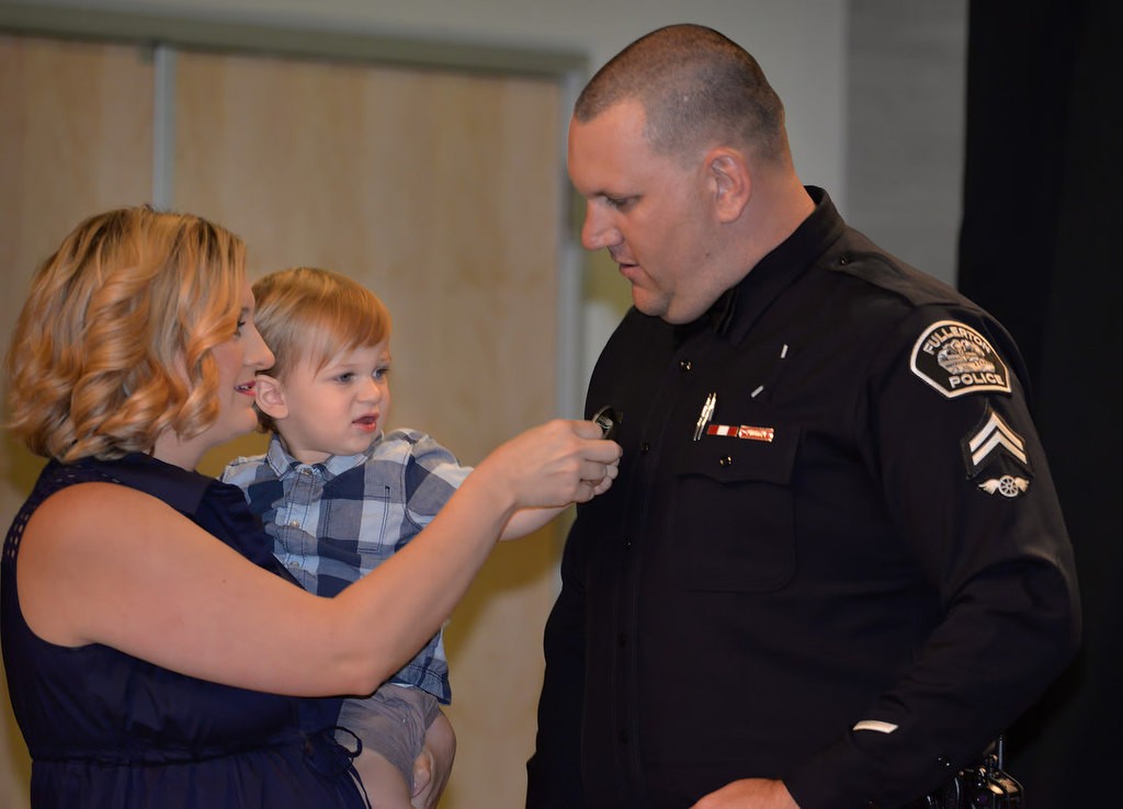 Fullerton PD Cpl. Kyle Baas receives his new badge from his wife Jeannette, and son John William, during a promotional ceremony. Photo by Steven Georges/Behind the Badge OC
