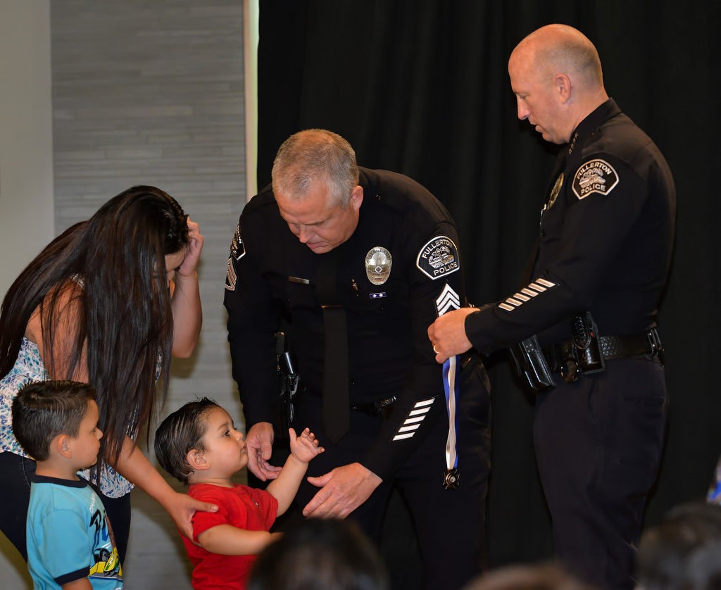 Sgt. Craig Odom is joined by his family as he receives the Life Saving Medal from Chief Dan Hughes for saving a 16-month old boy choking at a local restaurant.  Photo by Steven Georges/Behind the Badge OC