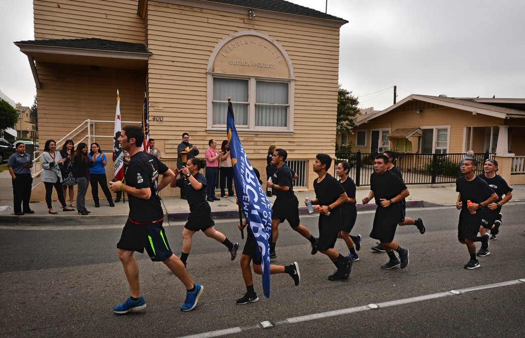 Anaheim Police Explorers from Post 249 and Anaheim PD officers run past the Anaheim Police Department (behind photographer) on Harbor Blvd. as employees from APD cheer them on during the Law Enforcement Torch Run for Special Olympics of Southern California. Photo by Steven Georges/Behind the Badge OC