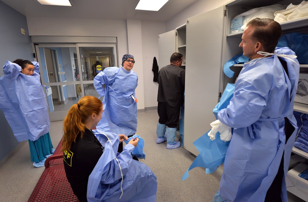 Lori Bair, forensic assistant I for the Orange County Sheriff Coroner, center standing, dresses in her scrubs as the team gets ready to perform the day’s autopsies. Photo by Steven Georges/Behind the Badge OC