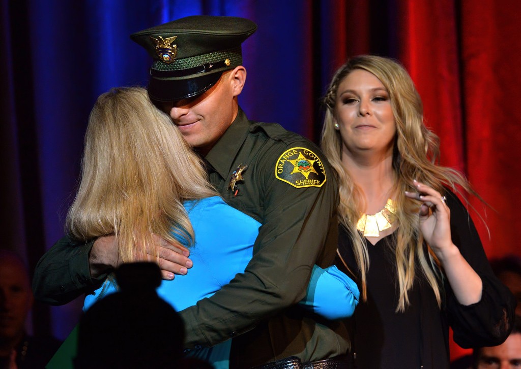 OCSD Deputy Steven Gibson gets a hug from mother Susan with his wife Jacqulyn behind him after receiving his new badge during graduation ceremonies. Photo by Steven Georges/Behind the Badge OC