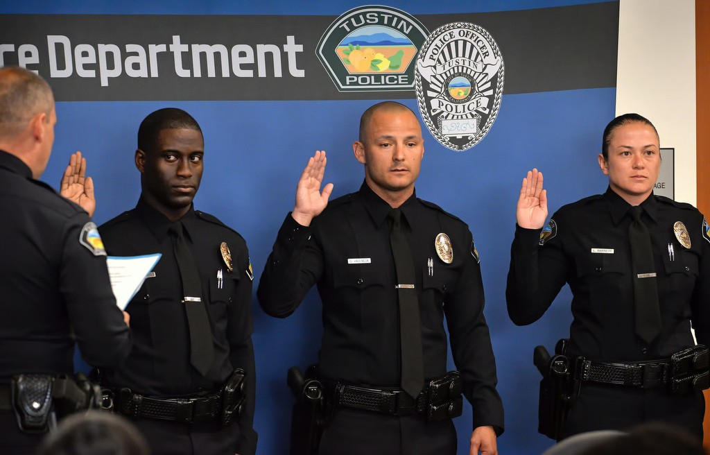 Tustin Police Chief Charles Celano, left, performs the official swearing in of officers Ismael Aurelus, David Valencia and Leah Barrett, right, during a small Tustin PD ceremony after the Orange County Sheriff's Regional Training Academy graduation ceremony. Photo by Steven Georges/Behind the Badge OC