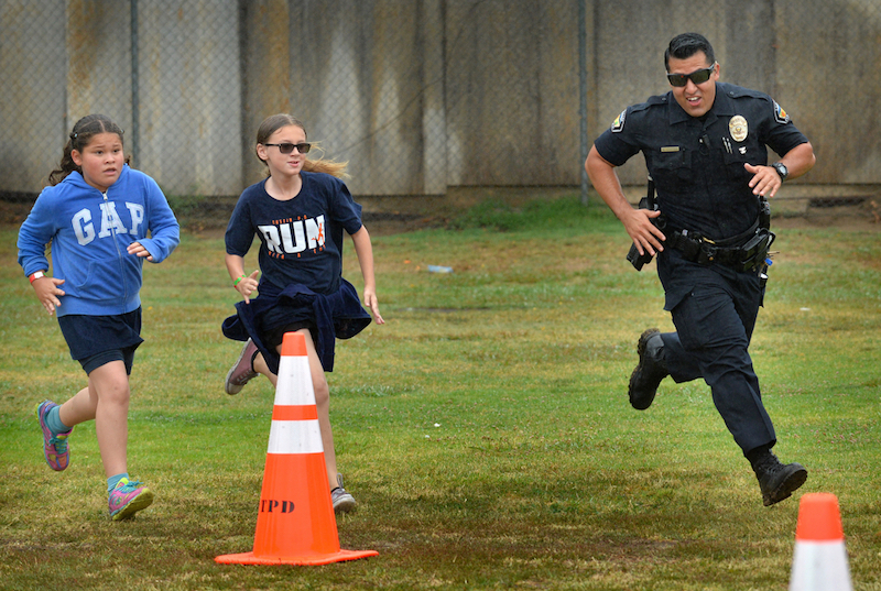 Tustin PD Officer Michael Carter runs with kids from Robert Heideman Elementary during the Tustin PD’s Run Club. Photo by Steven Georges/Behind the Badge OC