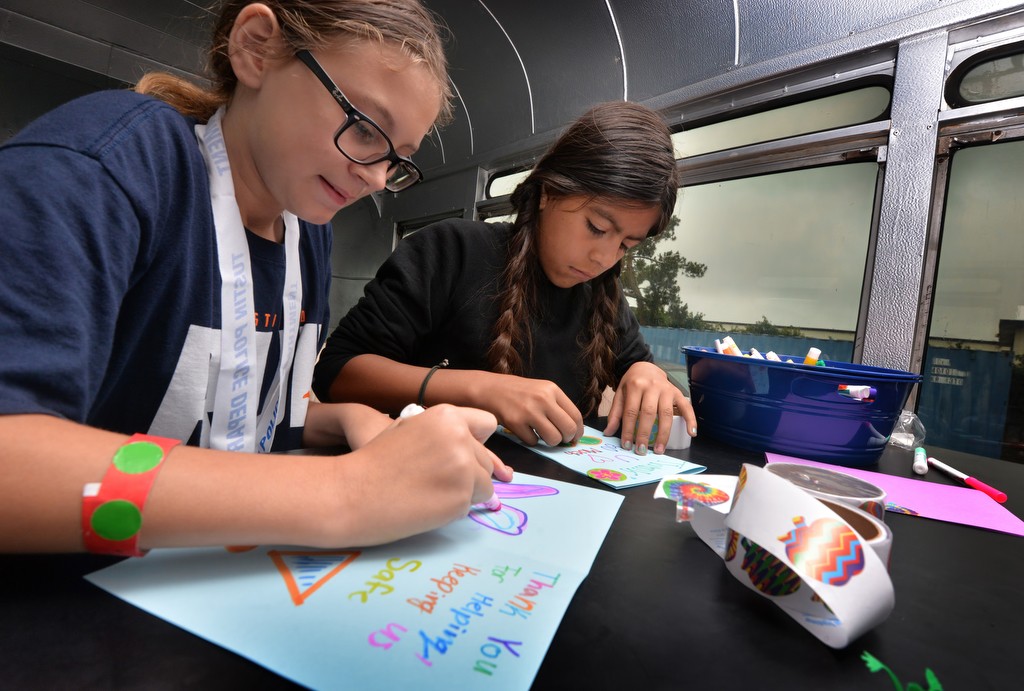 Cali Fields, 10, left, and Vanessa Pinzon, 12, write thank you cards to the Tustin Police from inside the Team Kids bus during the Tustin PD’s Run Club at Robert Heideman Elementary. Photo by Steven Georges/Behind the Badge OC