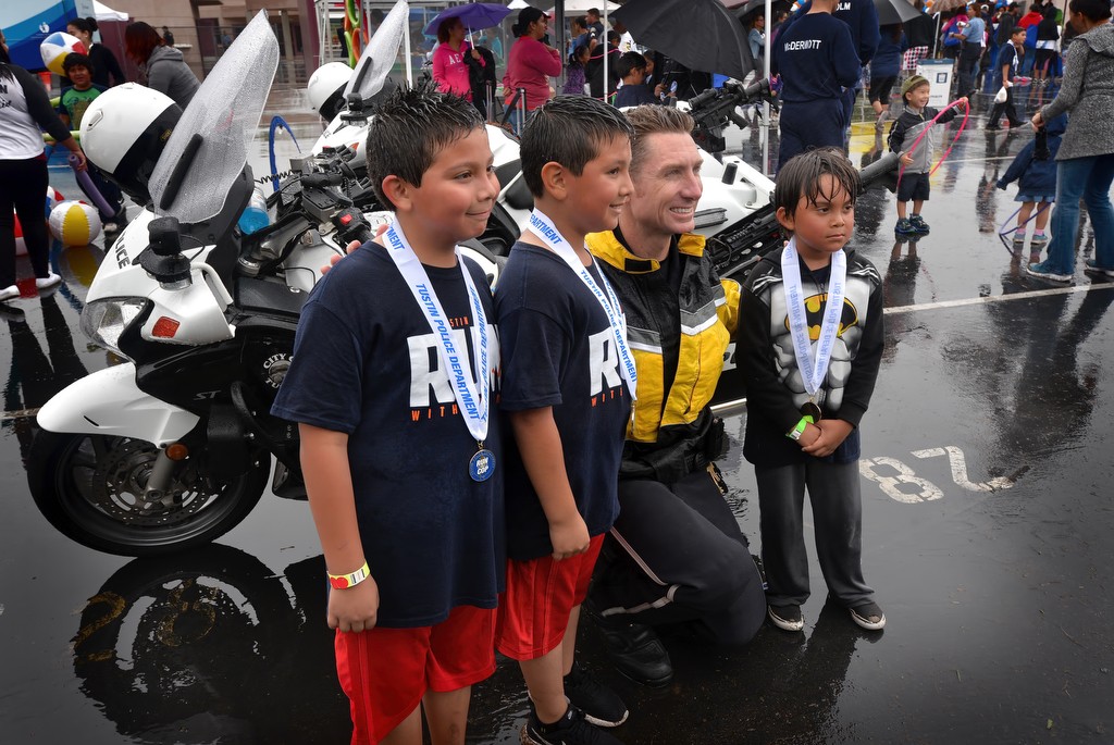 Tustin PD Officer John Hedges posses for photos with Sergio Ibarra, 8, left, Jose Ibarra, 7, and Octavio Bergara, 6, during Tustin PD’s Run Club at Robert Heideman Elementary. Photo by Steven Georges/Behind the Badge OC