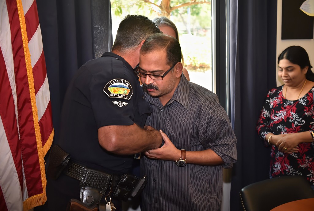 Tustin PD Officer Ralph Casiello gets a hug from Prabha Pelluru, the father of 13-year-old Siva Pelluru, who was saved by Officer Casiello after the boy collapsed due to a full cardiac arrest at Pioneer Middle School. Siva’s mother, Saraswathi Pelluru, is behind them, right. Photo by Steven Georges/Behind the Badge OC