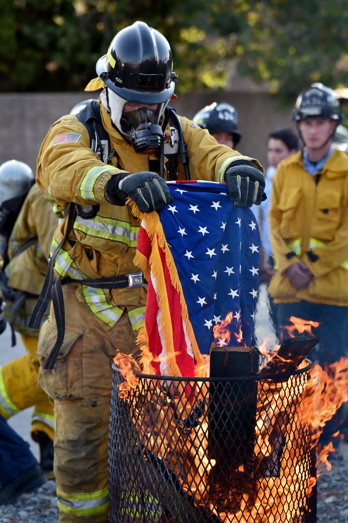 An Anaheim Fire & Rescue cadet places a flag into a fire for proper disposal, according to tradition, during a flag during ceremony in Anaheim. Photo by Steven Georges/Behind the Badge OC