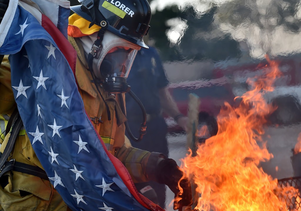 An Anaheim Fire & Rescue cadet places a flag into a fire for proper disposal, according to tradition, during a flag during ceremony in Anaheim. Photo by Steven Georges/Behind the Badge OC