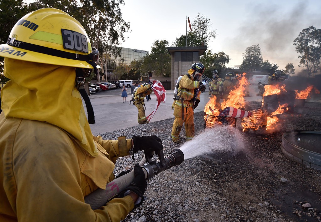 Andy Ingram, of Anaheim Fire & Rescue puts some water on the fire to keep it from getting too hot as cadets proceed with the proper disposal of American flags during a flag burning ceremony at the North Net Fire Training Center in Anaheim. Photo by Steven Georges/Behind the Badge OC